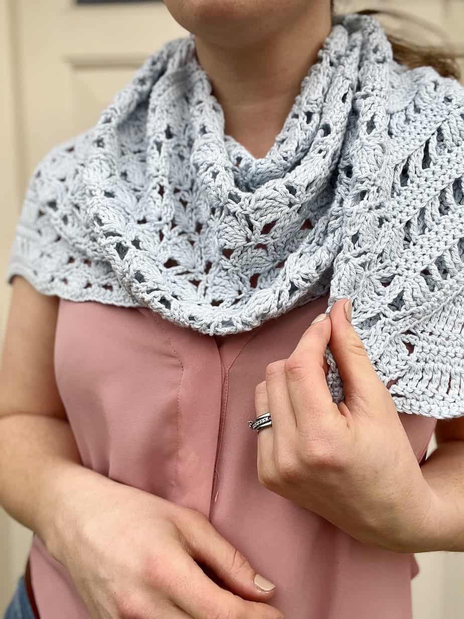 close up of person wearing blue lacy crochet shawl as a cowl around neck