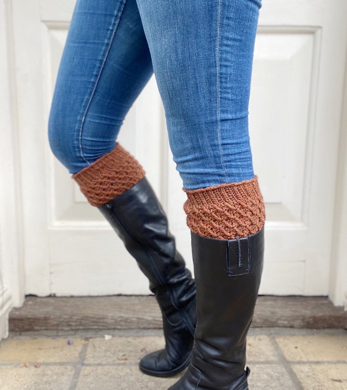 person wearing jeans, knee high boots and textured crochet boot cuffs in a rust colour