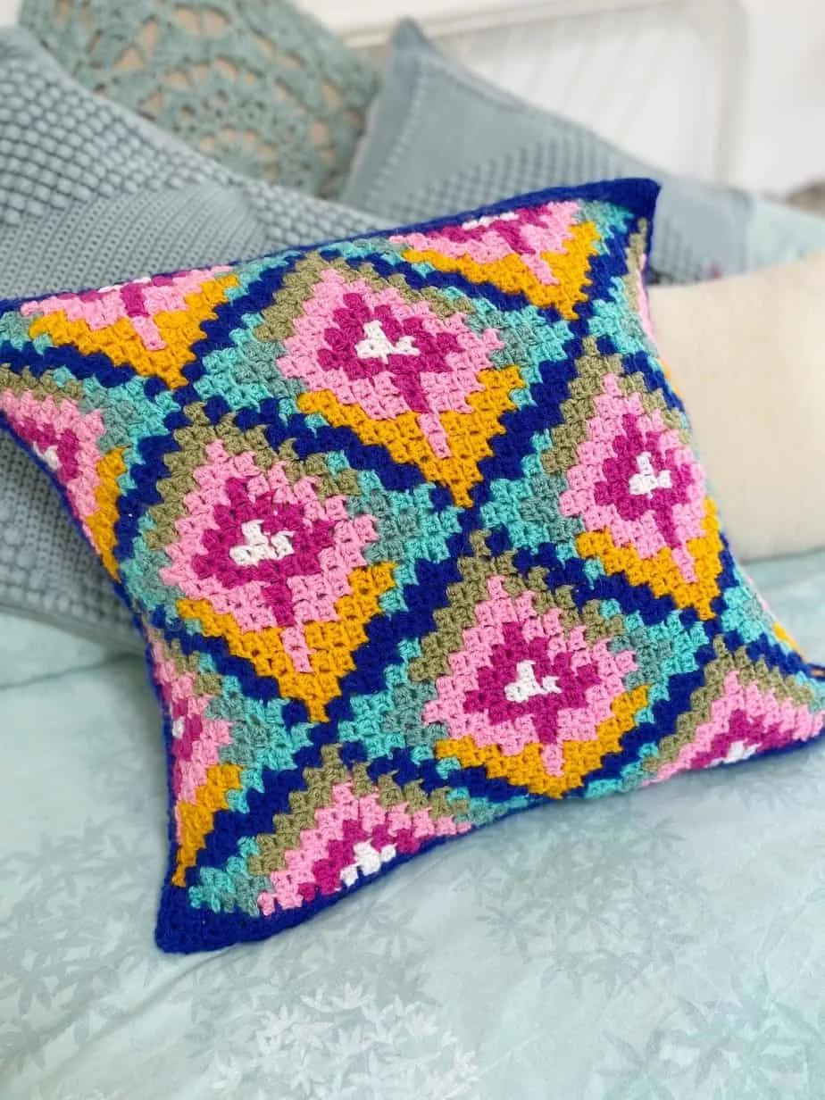 close up of corner to corner pillow in bright colours on a bed