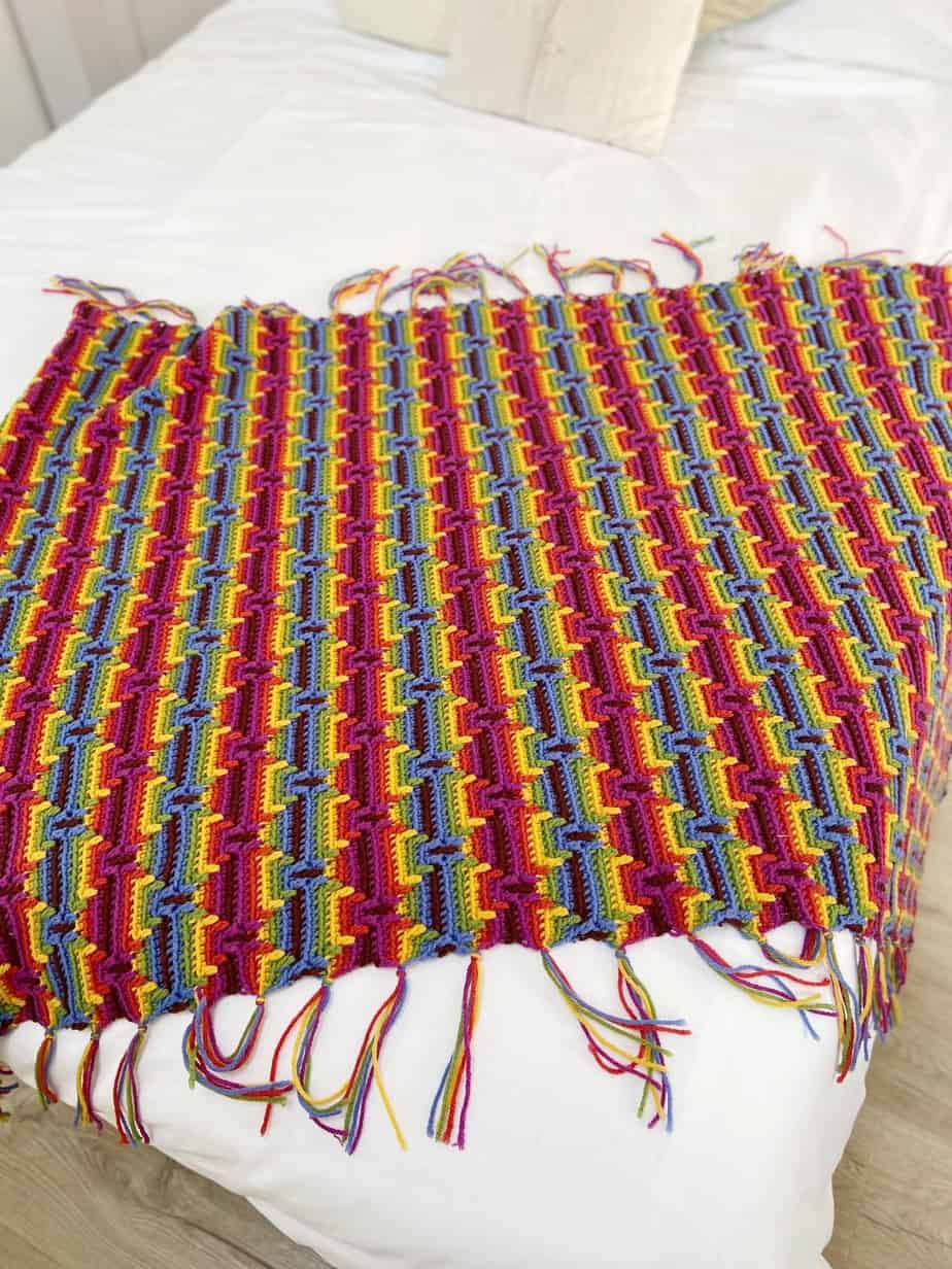 colourful overlay mosaic crochet blanket pattern laid flat on white bed