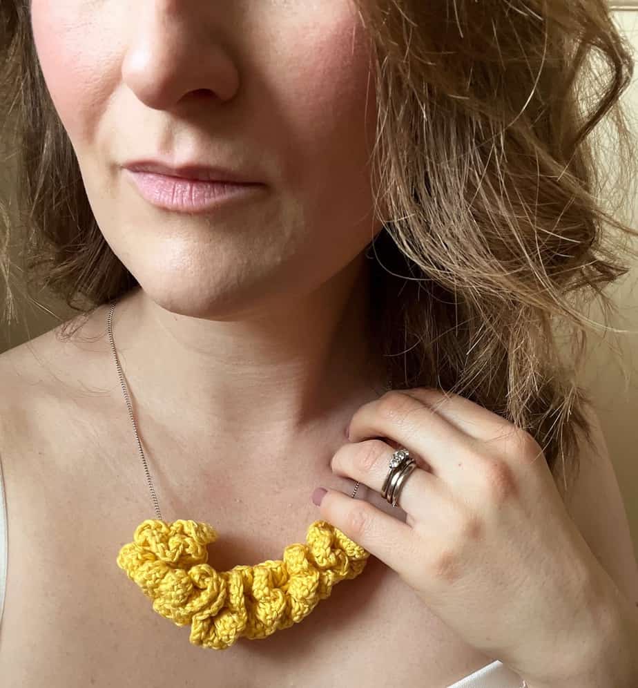 woman wearing yellow crochet necklace on silver chain with curly hair
