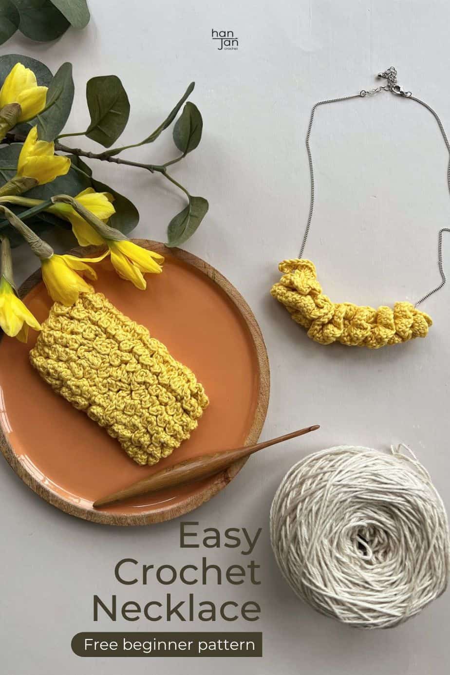 crochet necklace using ruffle stitch with cream yarn cake, wooden crochet hook and daffodils on table