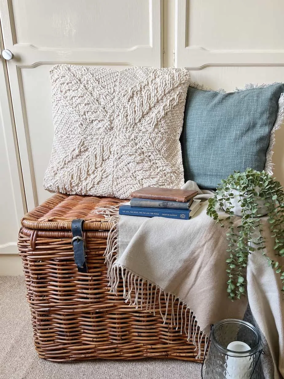 modern crochet pillow on large basket with plants and blanket