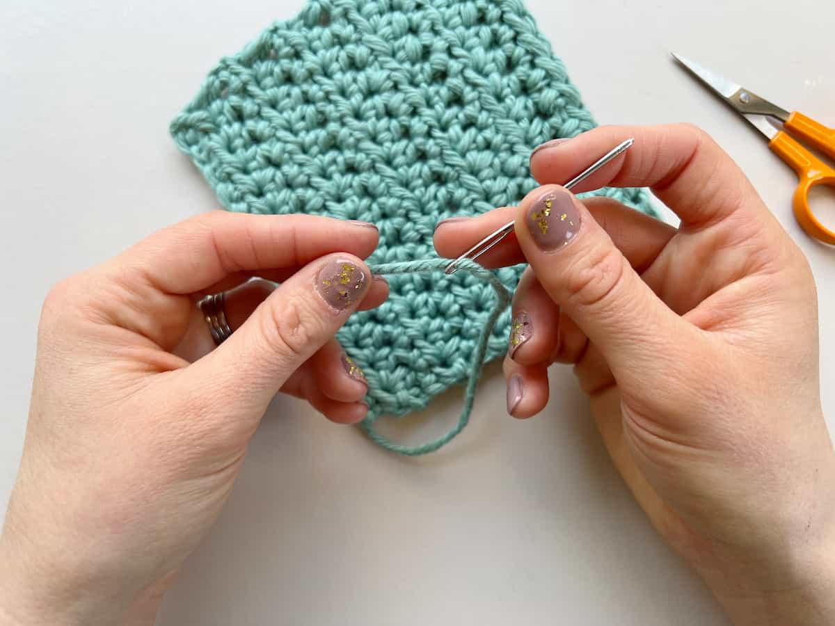 person threading a needle with blue yarn