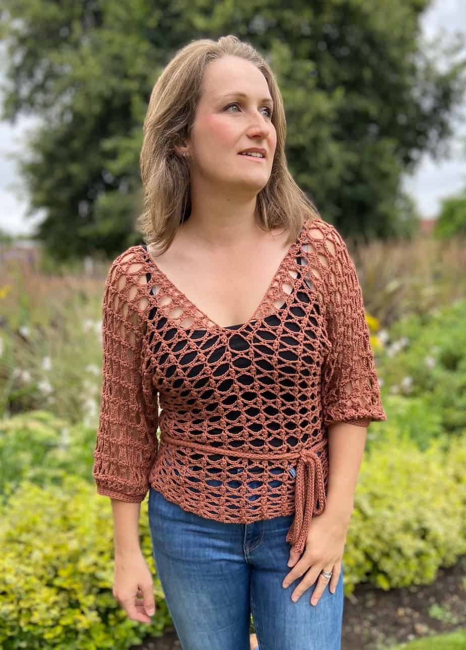 woman wearing lace crochet top over black tank top and jeans