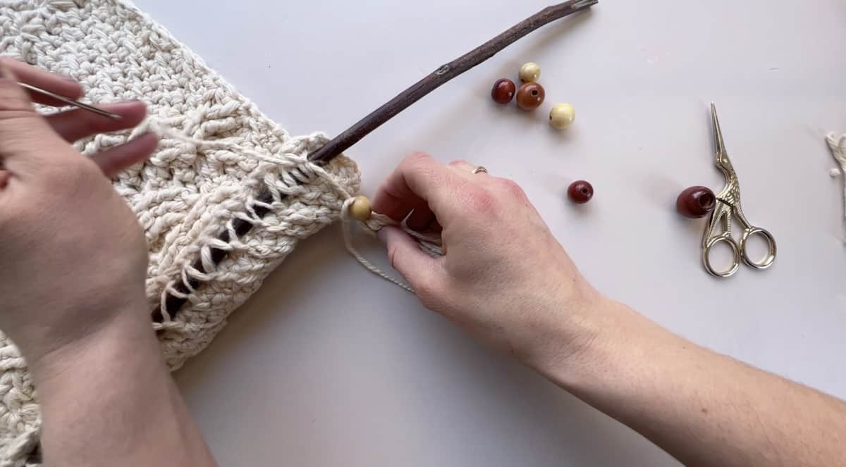 attaching a tassel and wooden beads to a boho crochet wall hanging