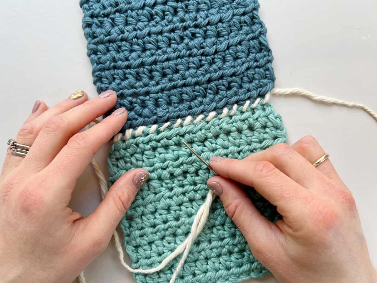 image showing a whip stitch crochet seam and hands holding needle