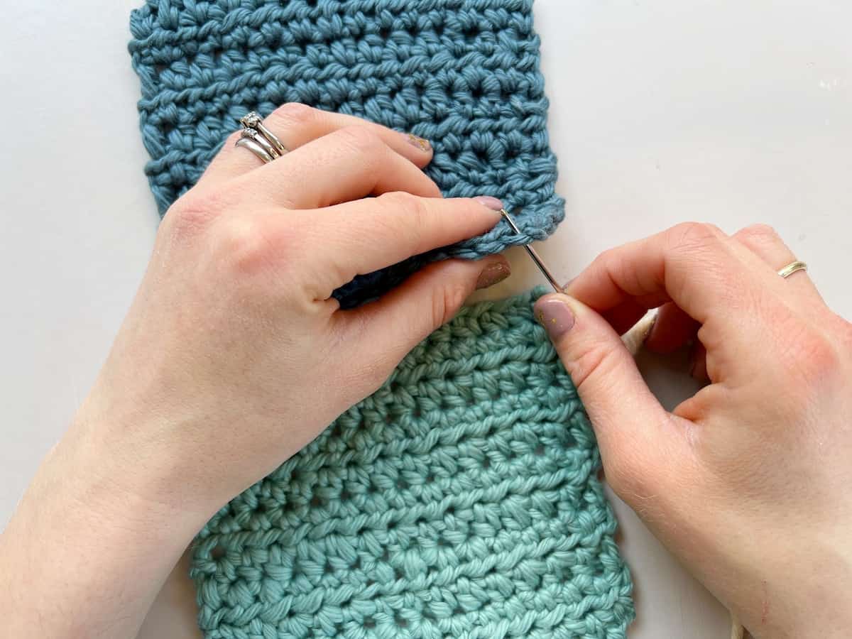 person putting needle into a crochet stitch to begin a whip stitch 