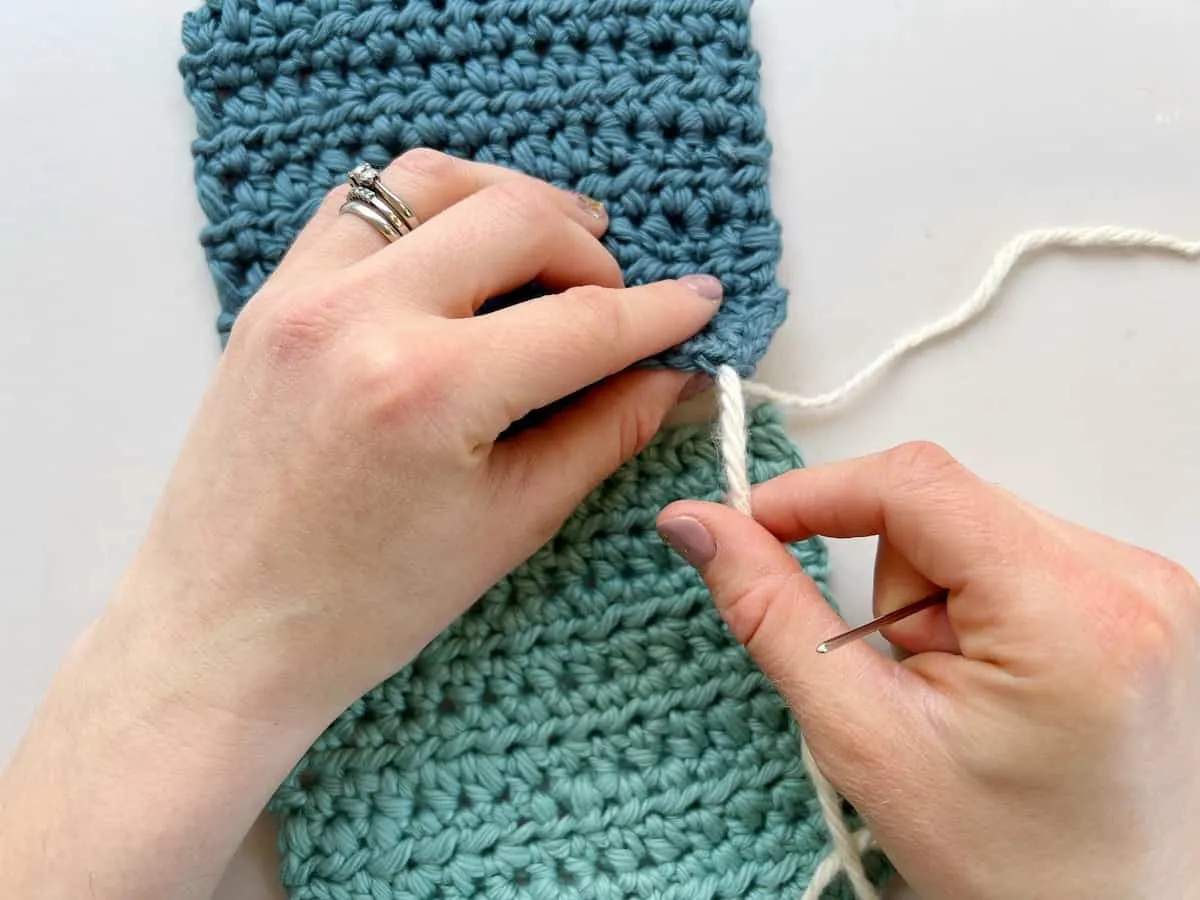 person pulling yarn through a crochet stitch to create a whip stitch