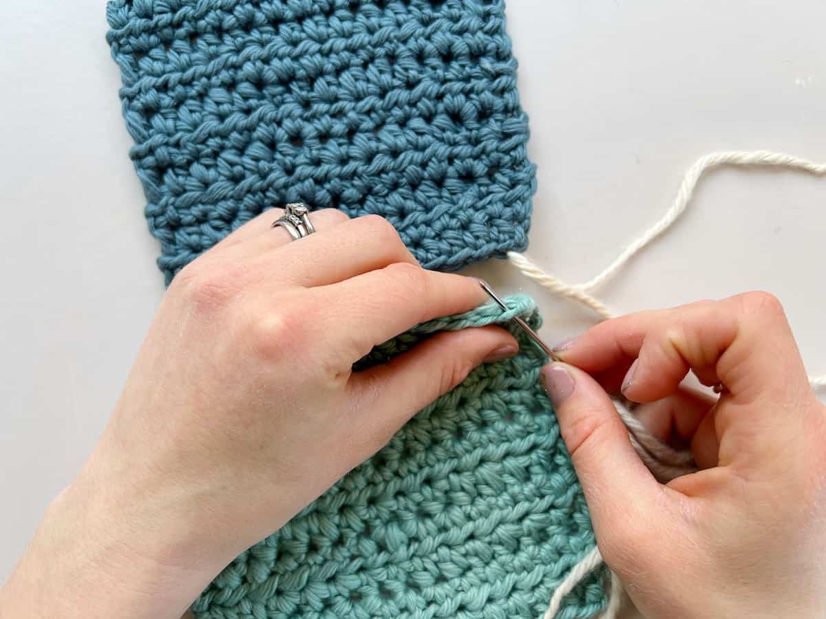 person inserting needle into 2nd piece of crochet to sew a whip stitch