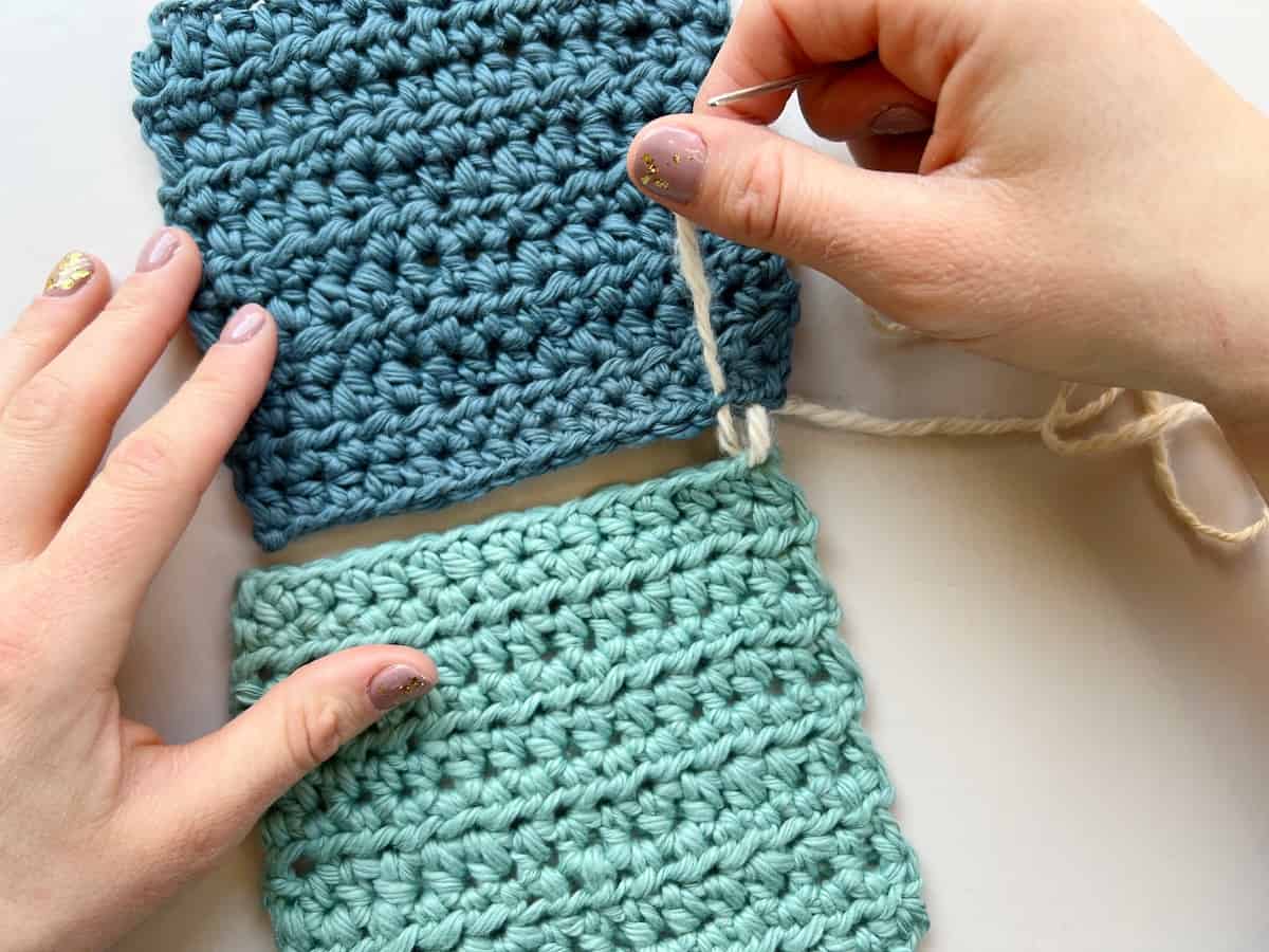 person pulling yarn through 2 stitches of crochet to make a whip stitch