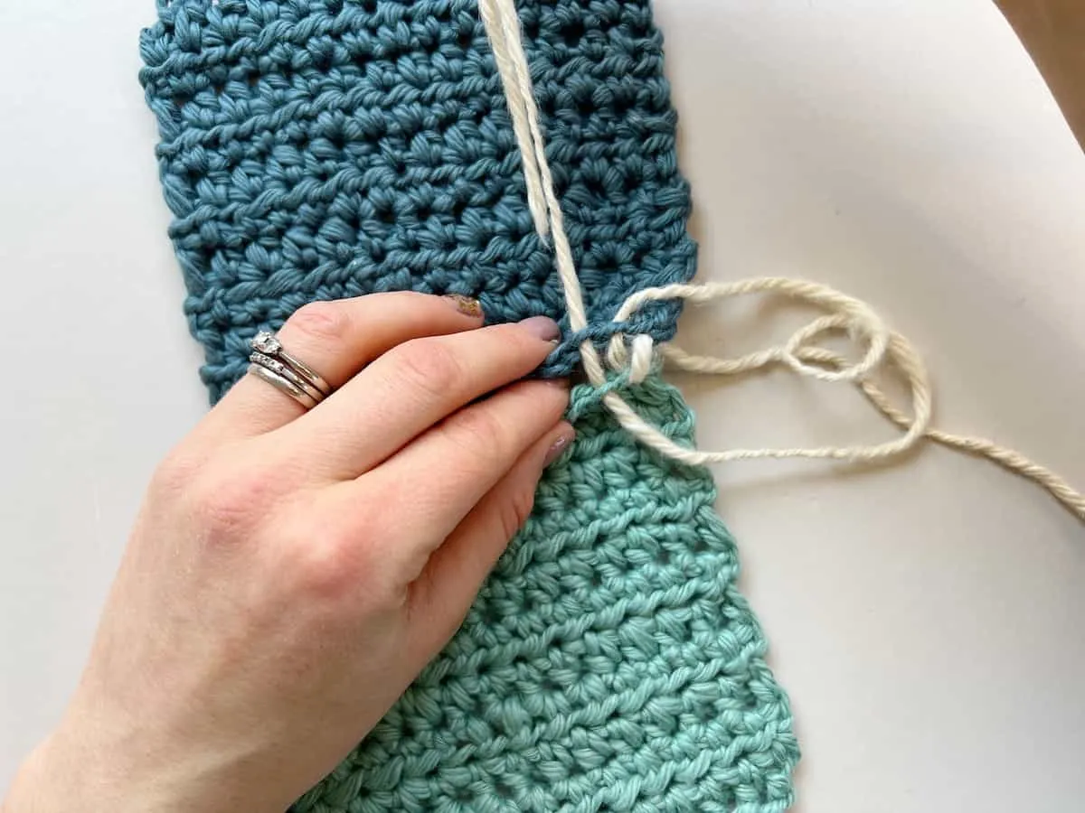 person pulling yarn through crochet seam
