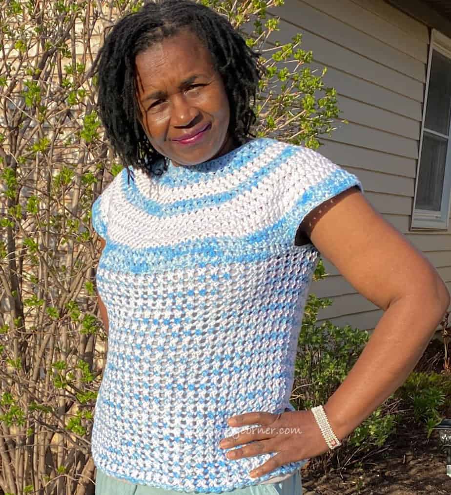 Woman with hands on hip wearing blue and white crochet summer top