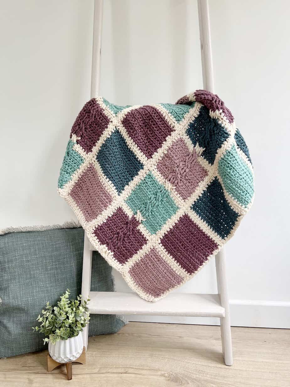 Bulky baby crochet blanket pattern hanging on ladder.