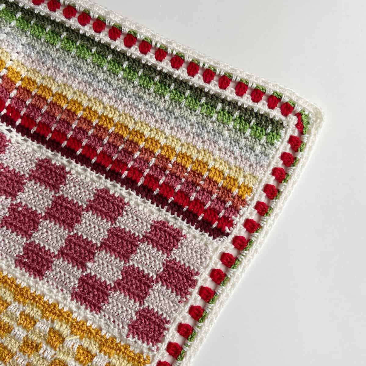 Close up of colorful crochet blanket pattern with strawberry crochet stitch border.