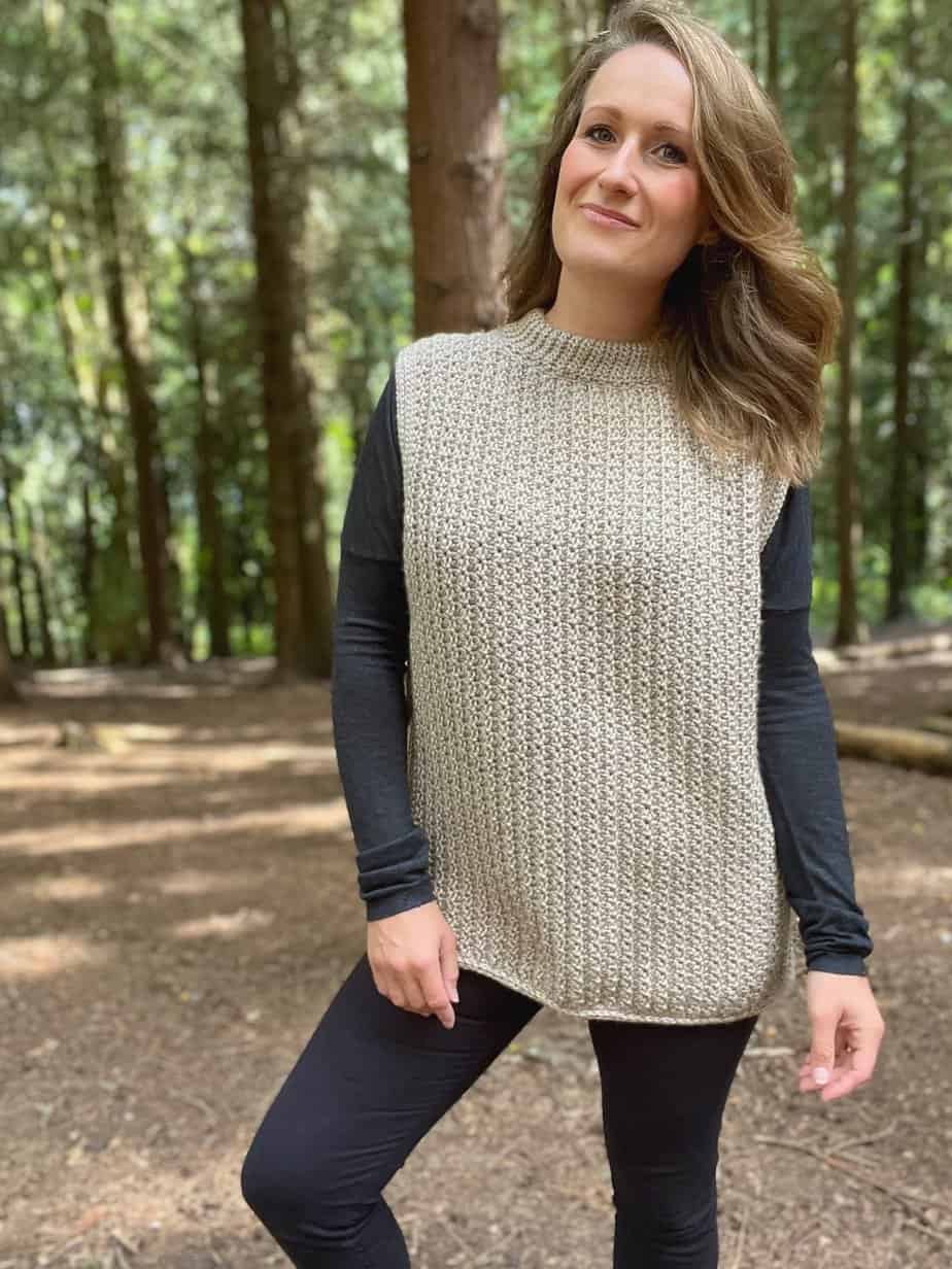 Woman in a forest wearing a cream loose fitting crochet poncho.