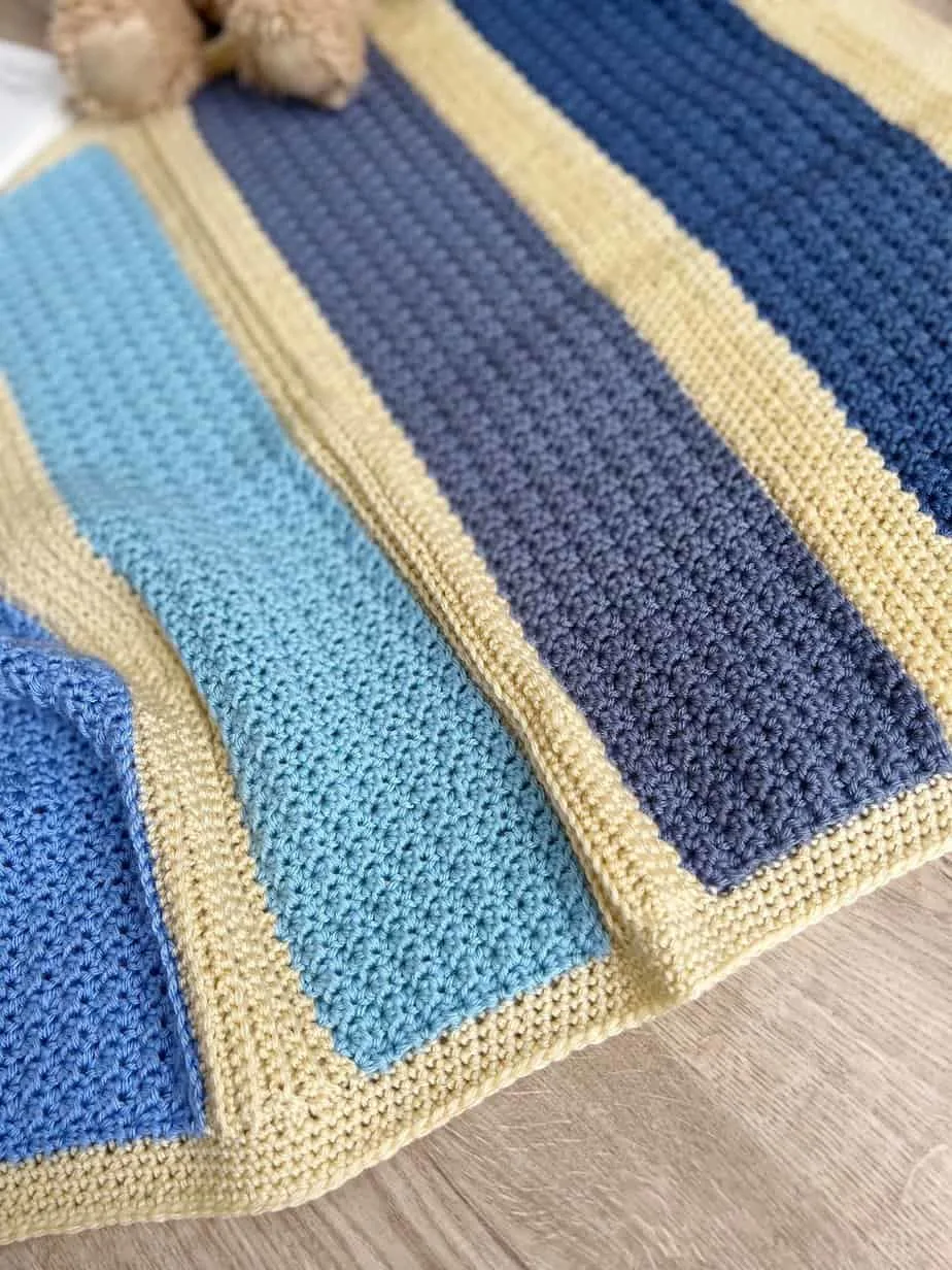 Modern crochet baby blanket pattern with blue yarn.