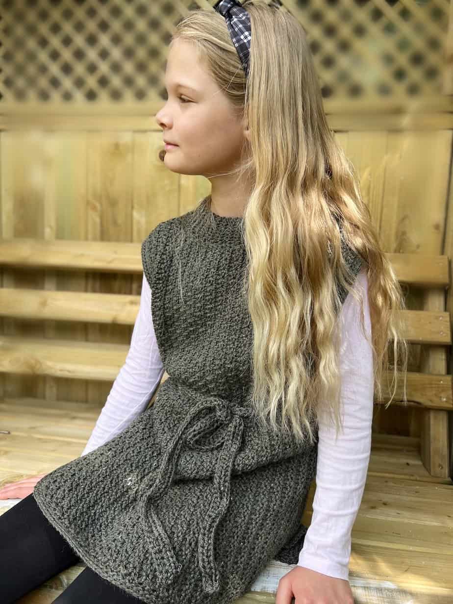 Girl with blonde hair wearing crochet tunic pattern with waist tie.