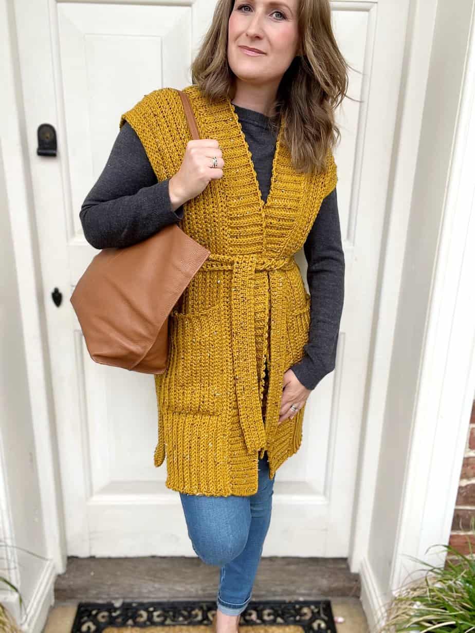 Woman wearing mustard sleeveless duster crochet vest.