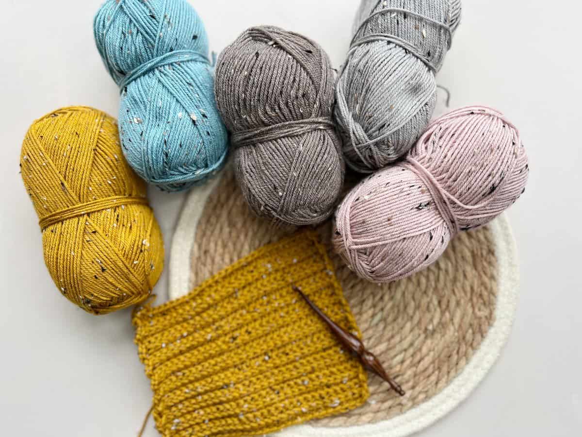 Balls of Brava tweed yarn in yellow, blue, mink, grey and pink.