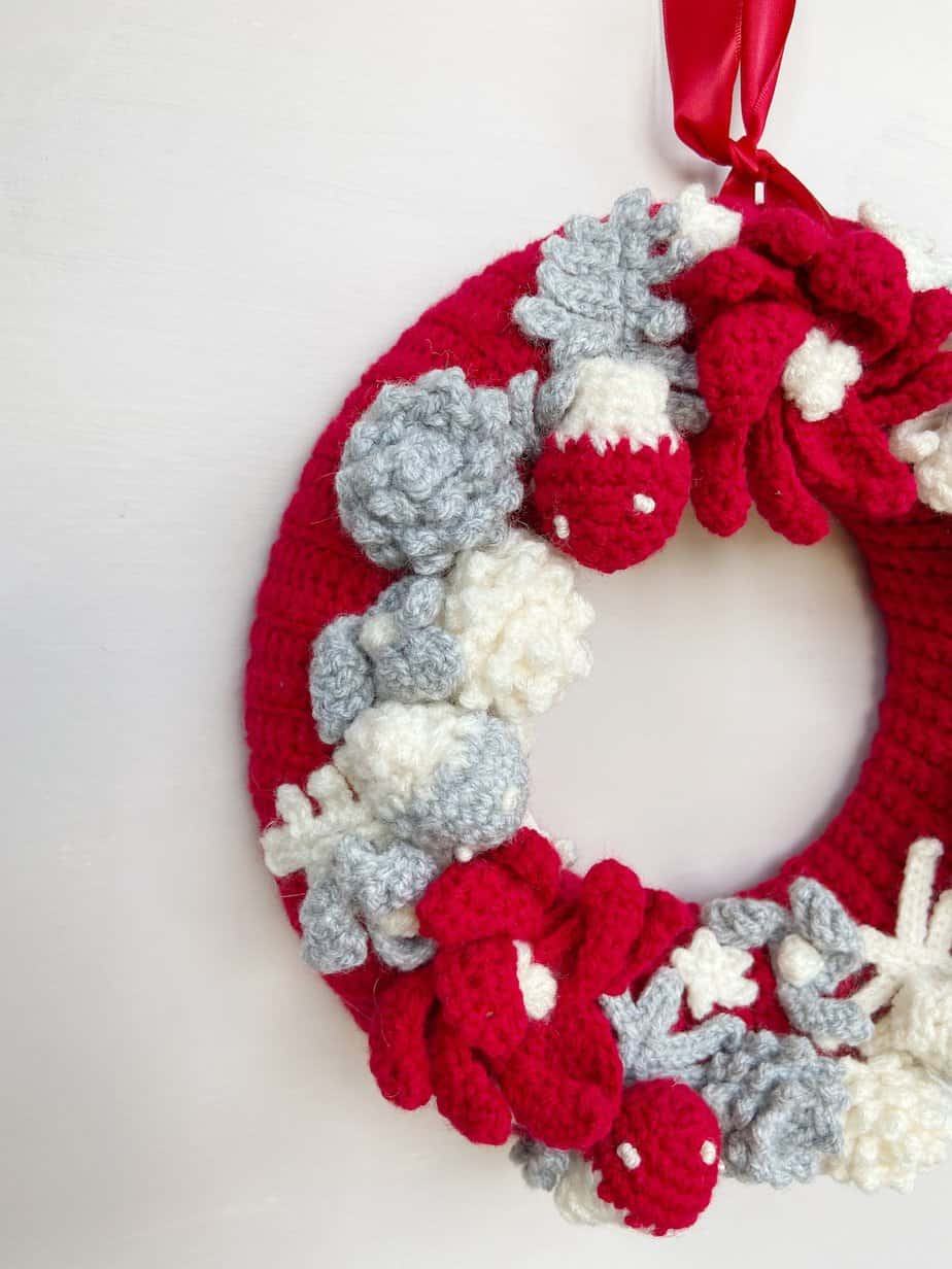 Crochet wreath with pine cones, toad stool and red cover.