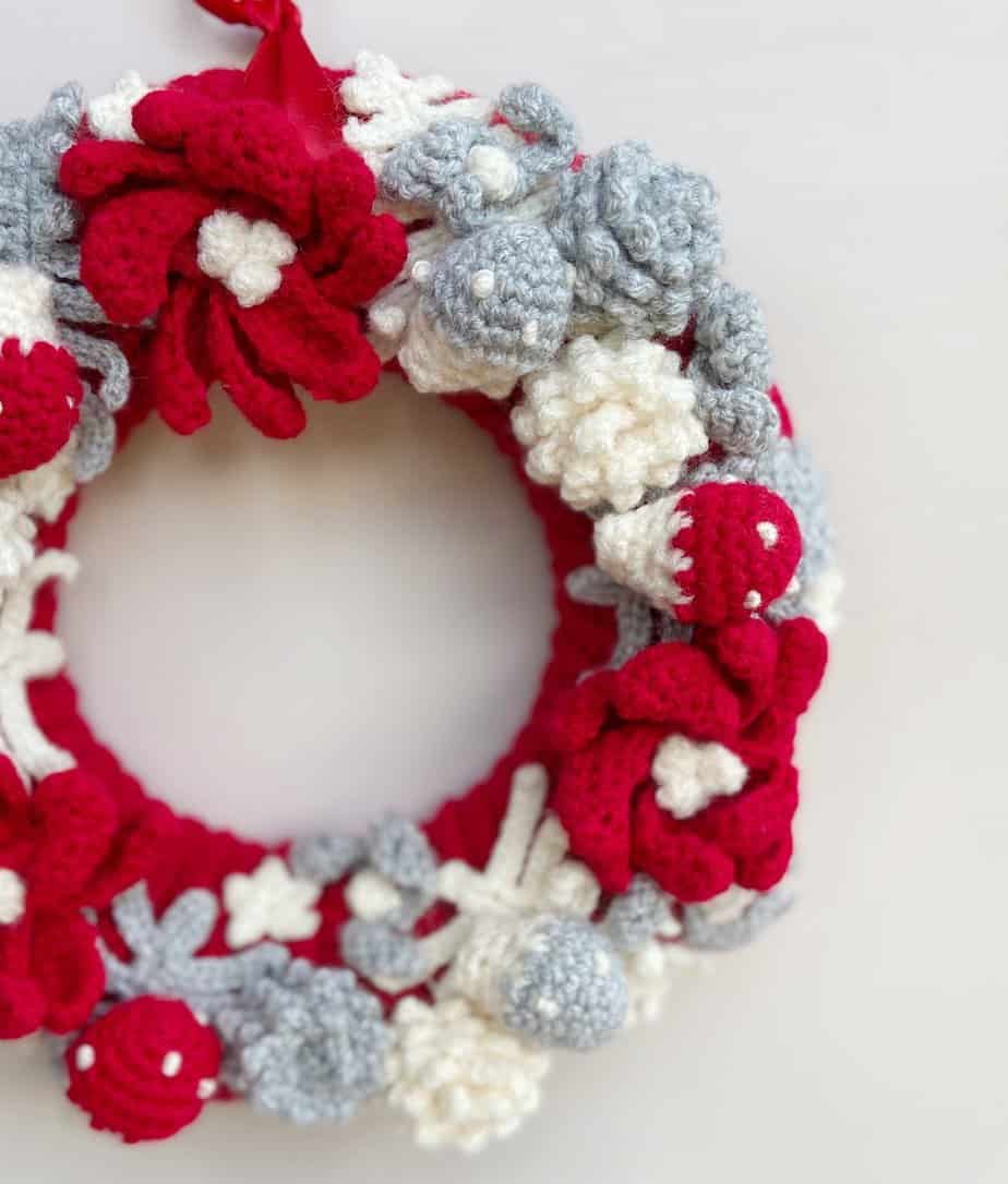 Close up of crochet wreath with toadstools and pine cones.