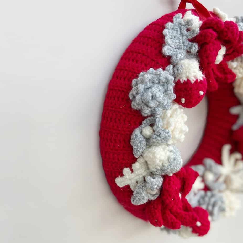 Side view of festive crochet wreath pattern in red, cream and grey.