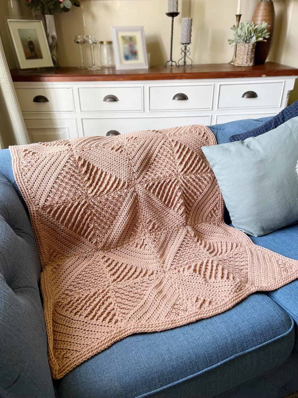 Textured crochet blanket laid over a sofa.