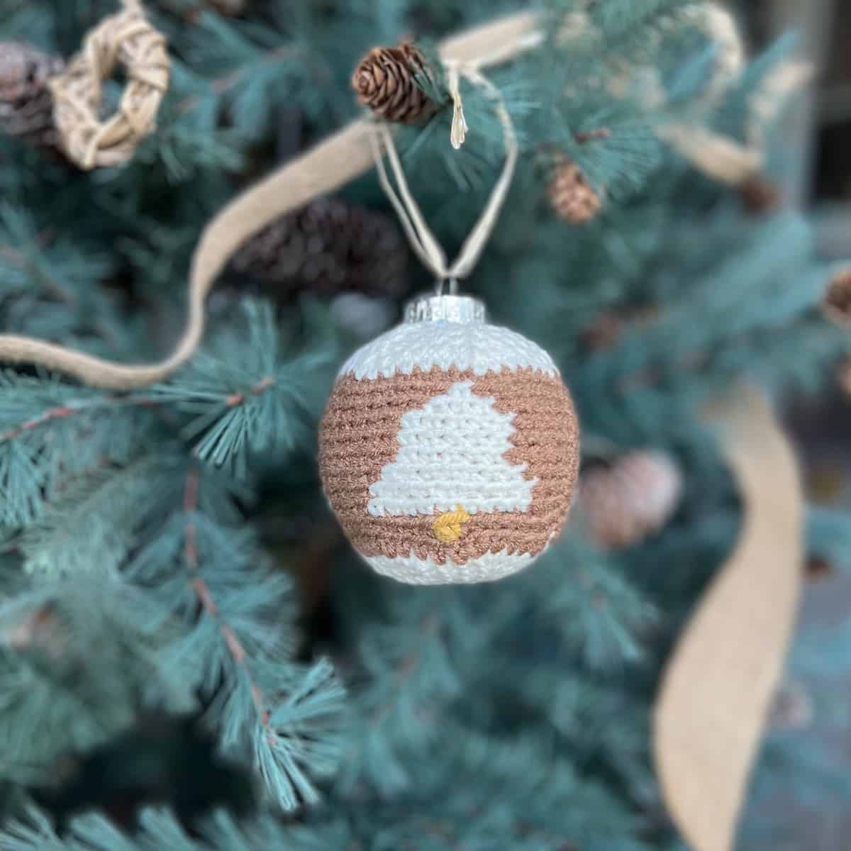 Crochet bauble pattern with bells on hanging on a tree.