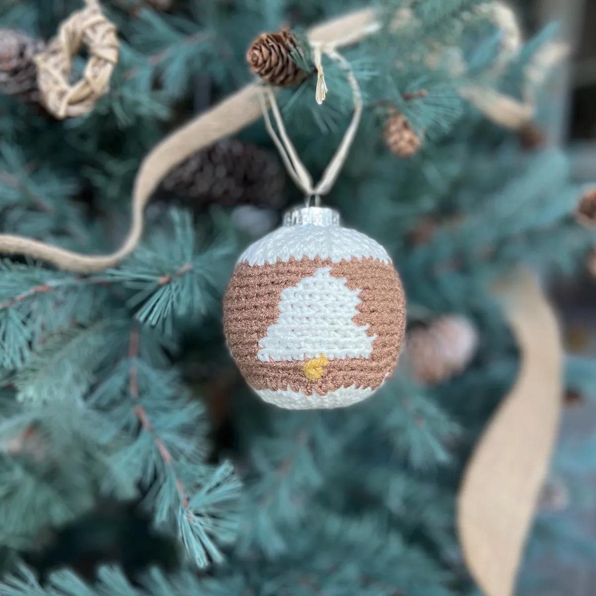 Crochet bauble pattern with bells on hanging on a tree.