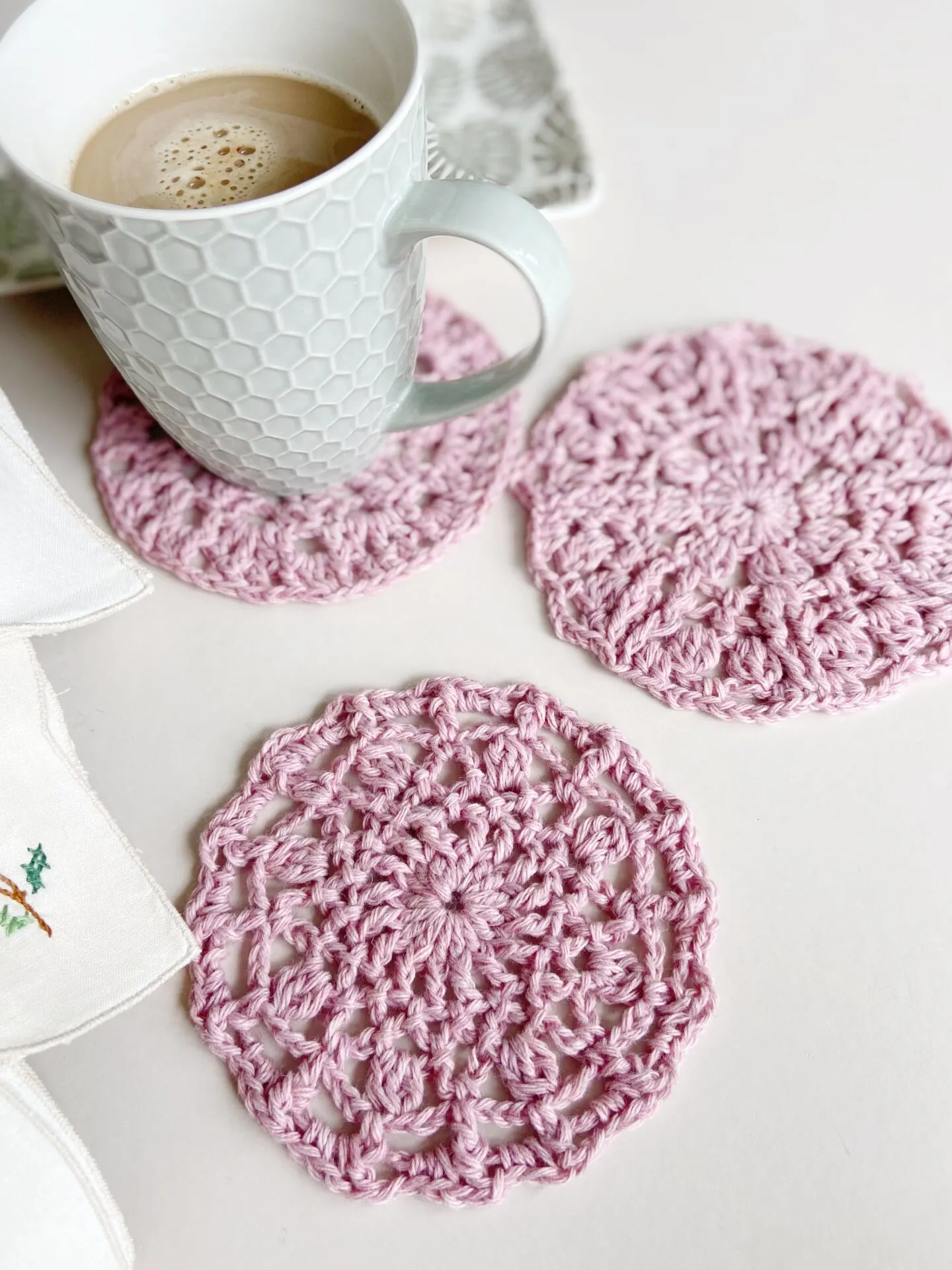 Lace crochet coaster pattern on table with tea cup.