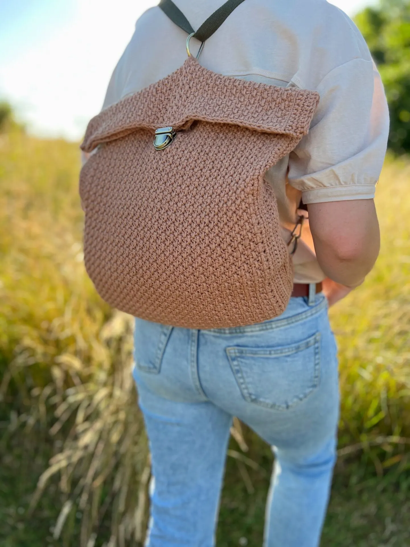 Person walking away wearing jeans and crochet backpack in brown.