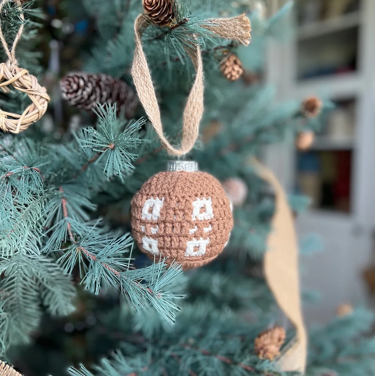Spots and squares on a crochet bauble hanging on a tree.