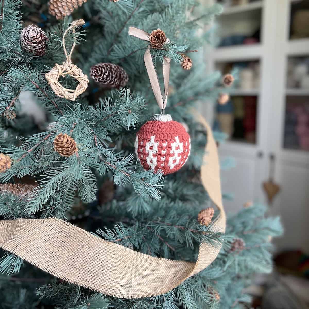 Overlay mosaic crochet bauble pattern hanging on tree.