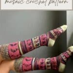 Person wearing colorful, knee-length crochet socks with mosaic patterns in pink, green, and purple, feet resting against a wall. Text above reads "Knee Length Crochet Socks – unique crochet sock pattern.