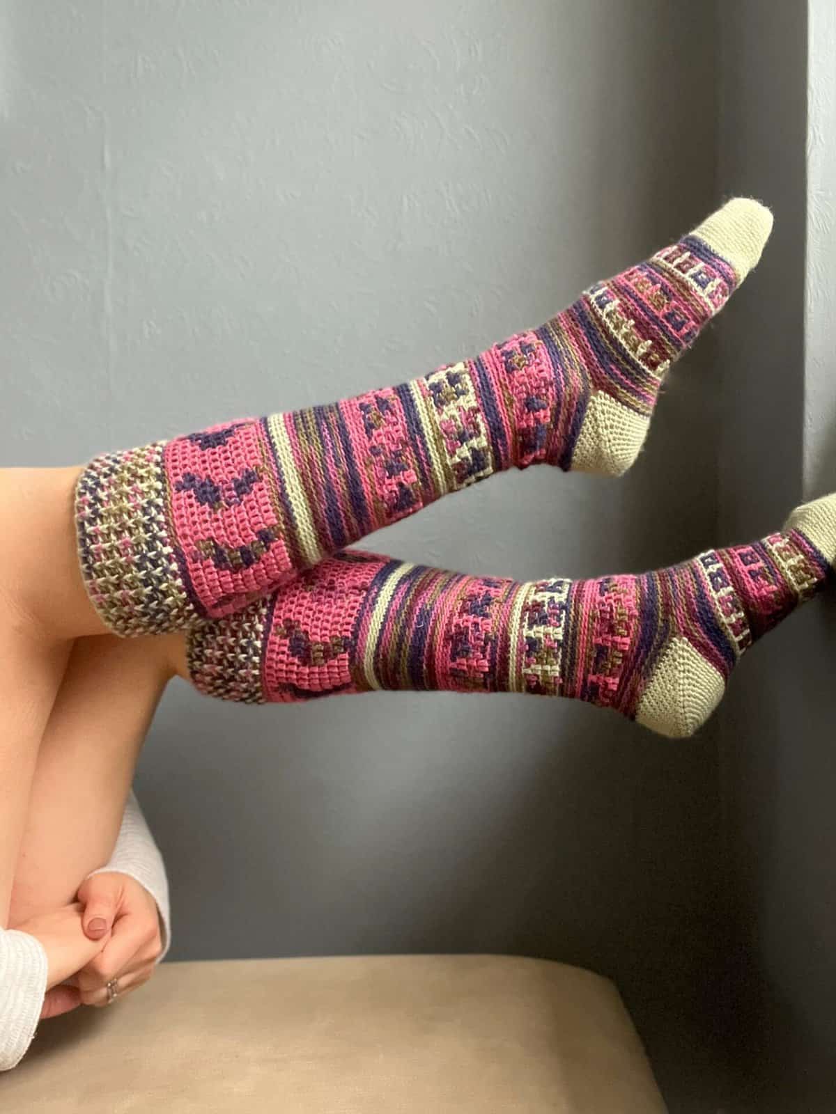 Person wearing colourful mosaic crochet socks.