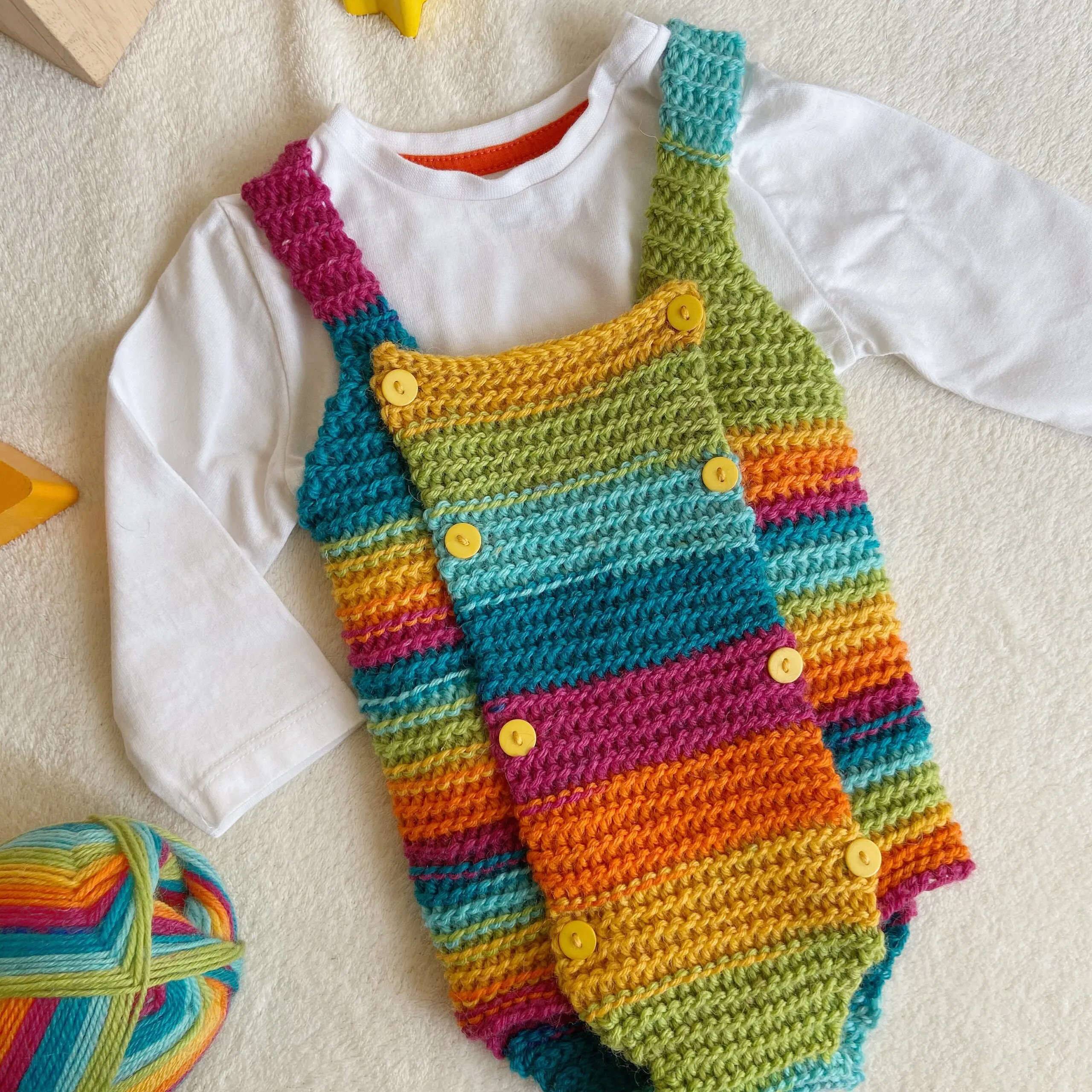 Rainbow baby crochet outfit with little yellow buttons.