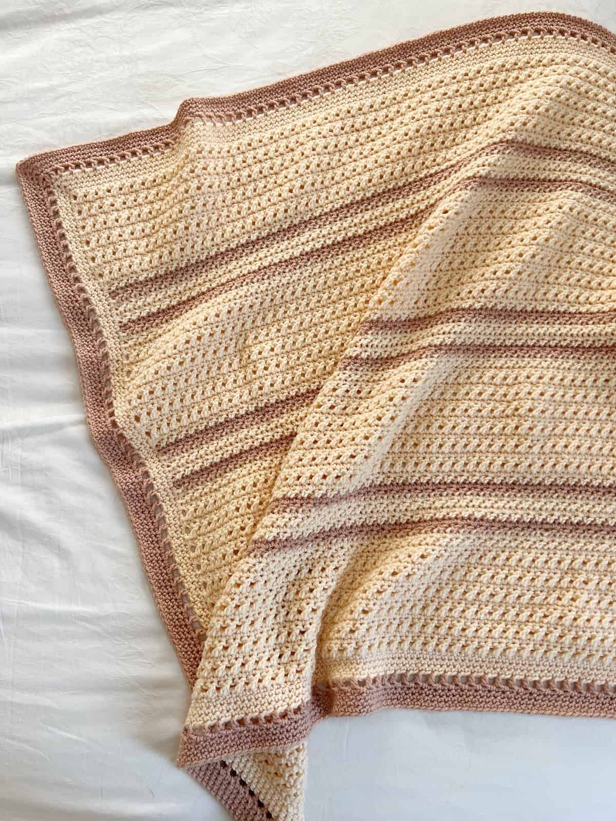 Traditional crochet baby blanket in cream and fawn.