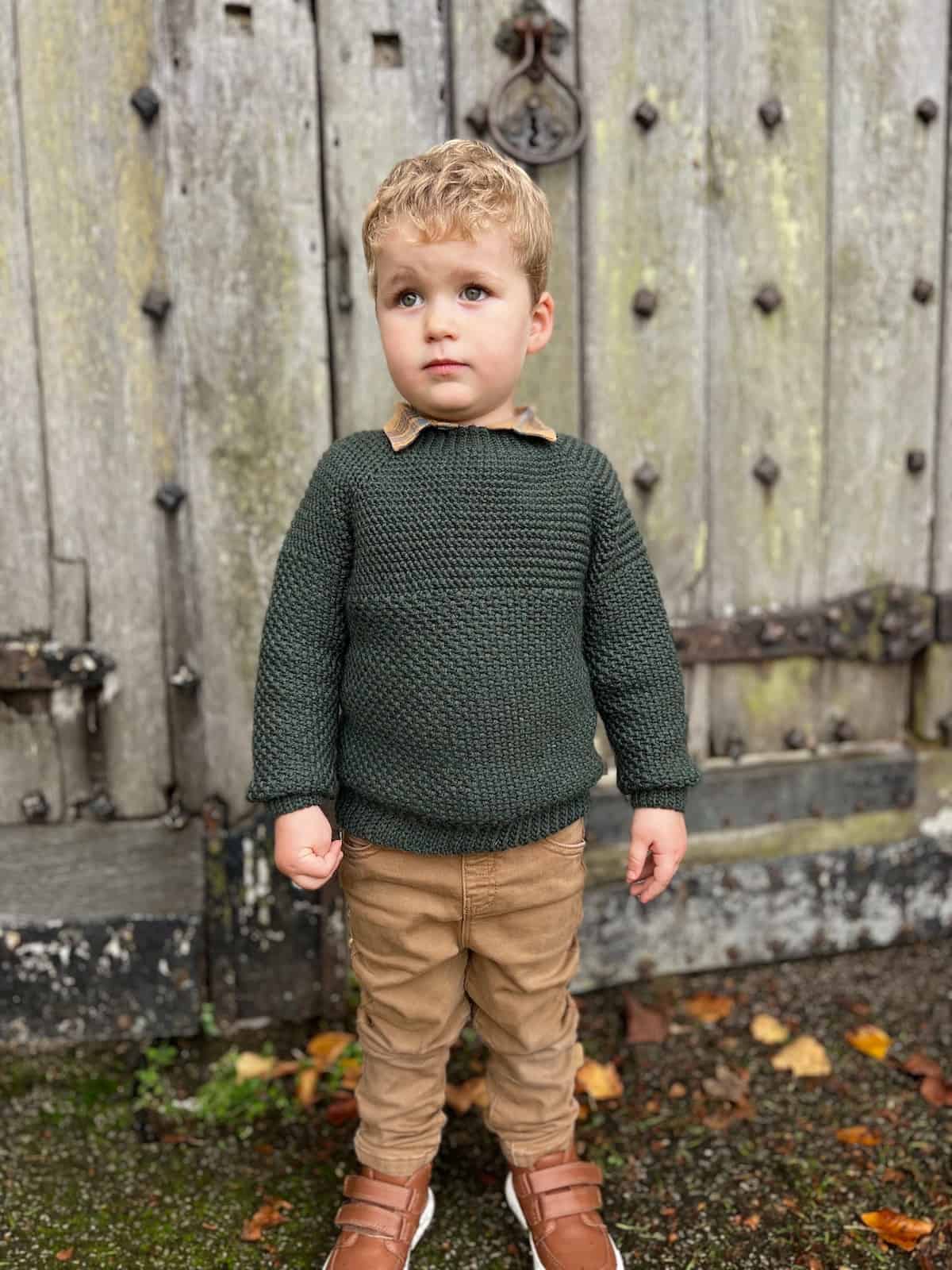 Toddler wearing green raglan crochet sweater.