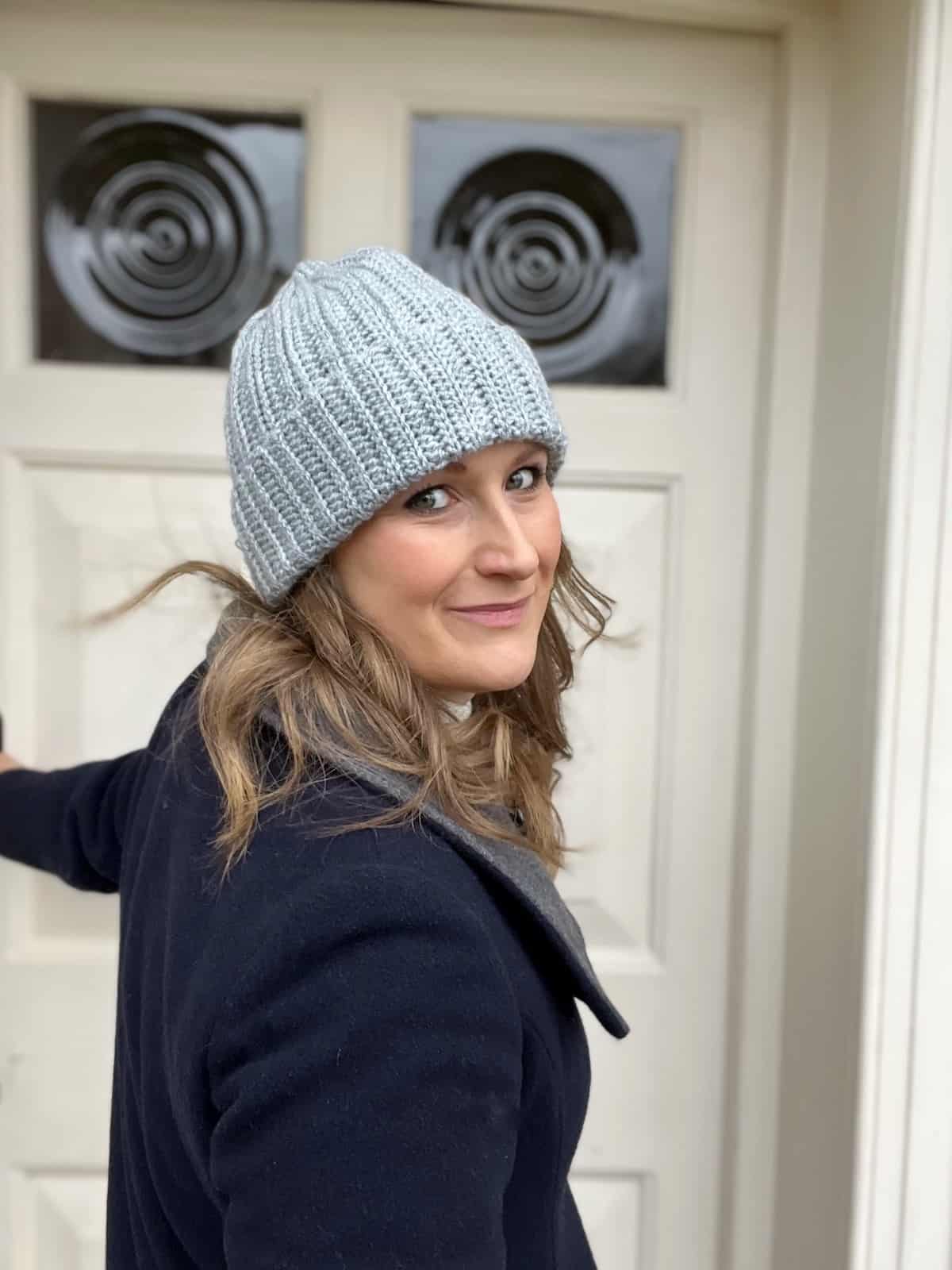 Woman wearing grey ribbed crochet hat pattern.