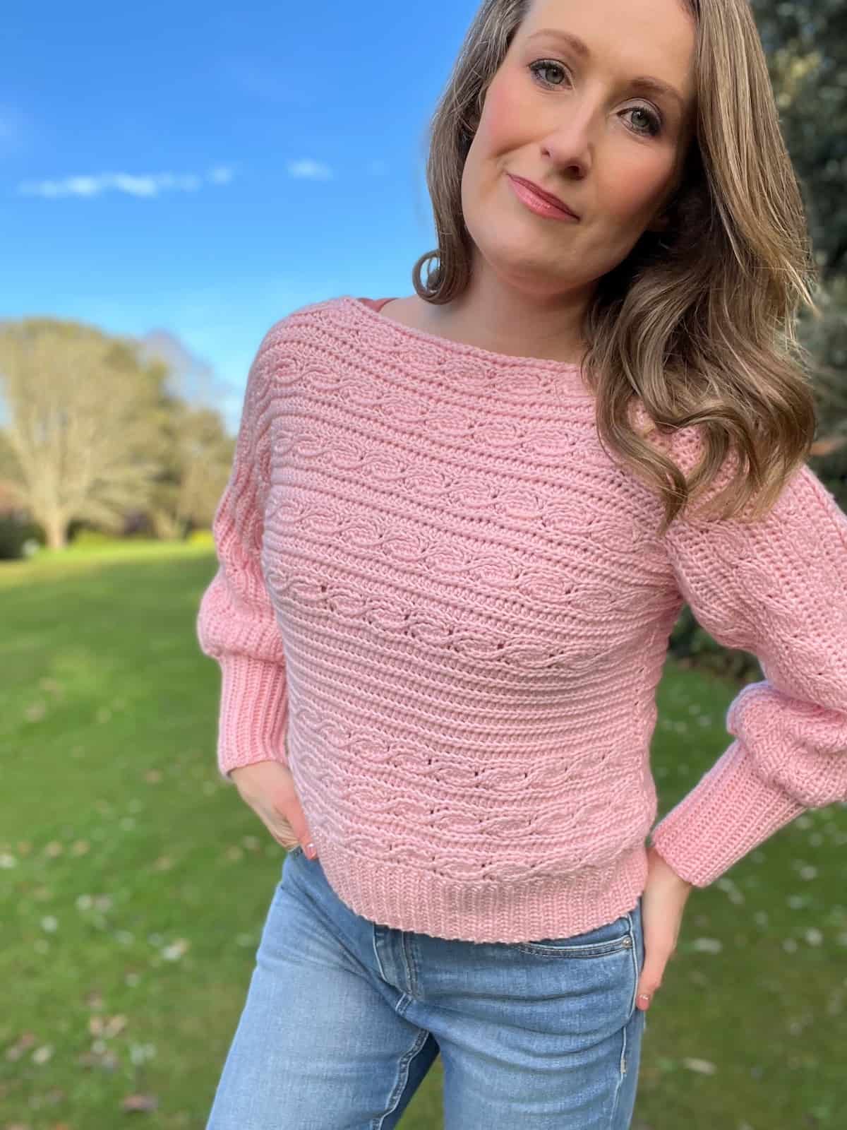 Woman wearing a pink crochet sweater that looks knitted.