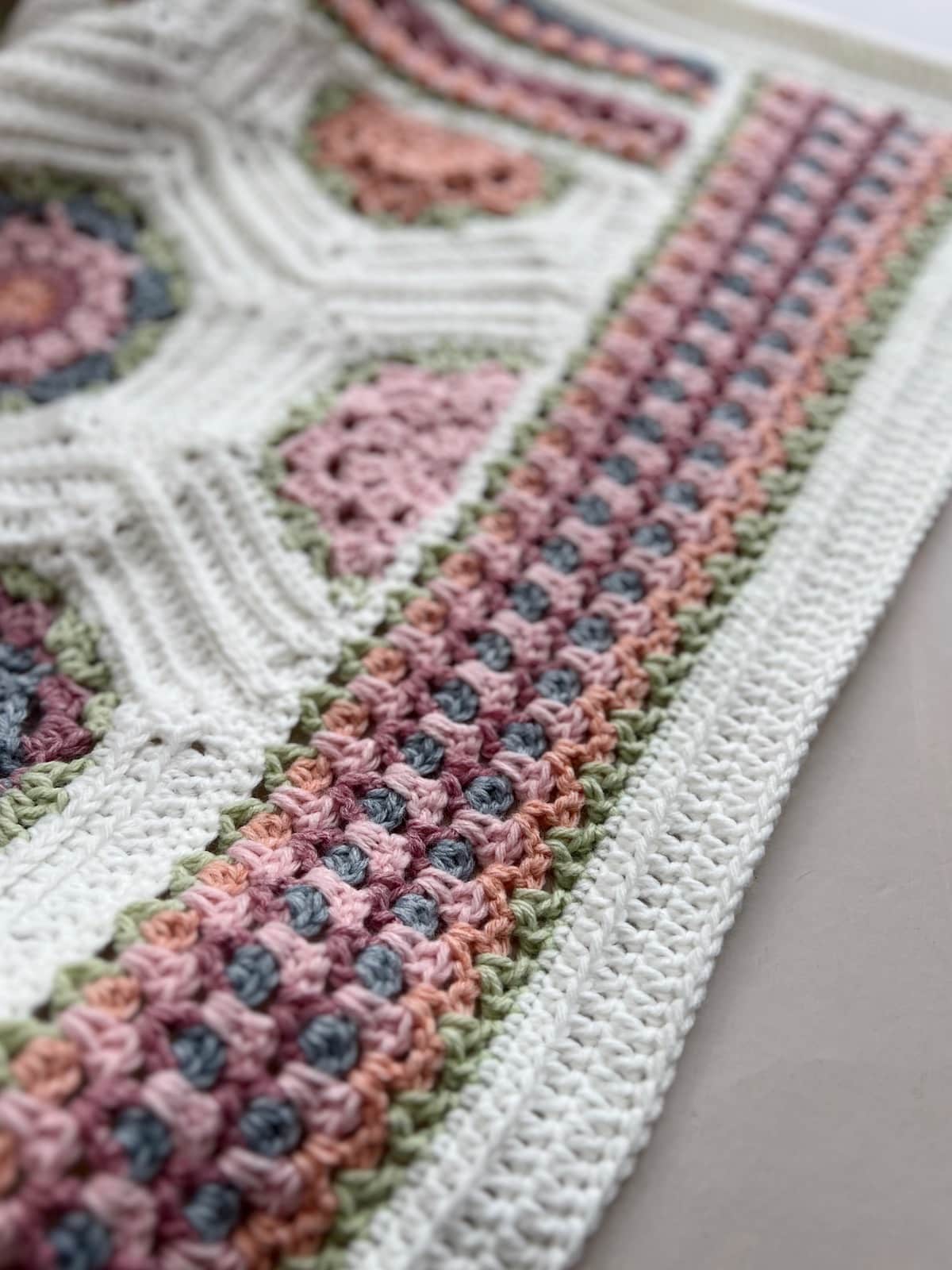 V stitch crochet border on a blanket in pastel colours.