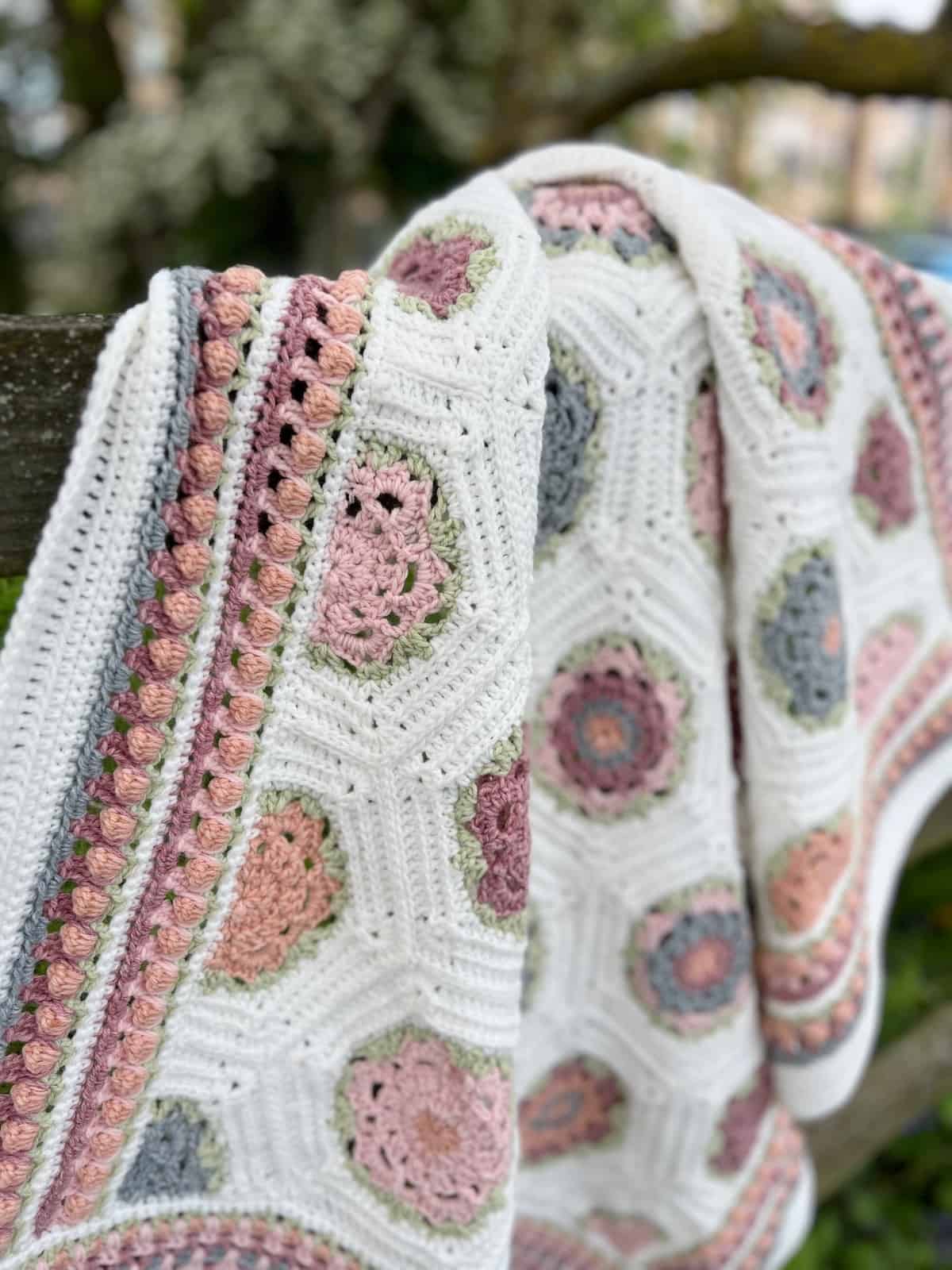 Flower crochet blanket laid over a gate.