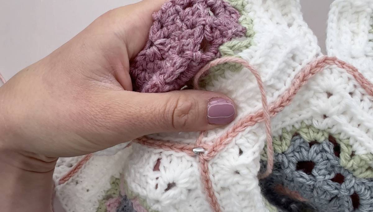 Crochet hook pulling yarn through a stitch on flat slip stitch seam.