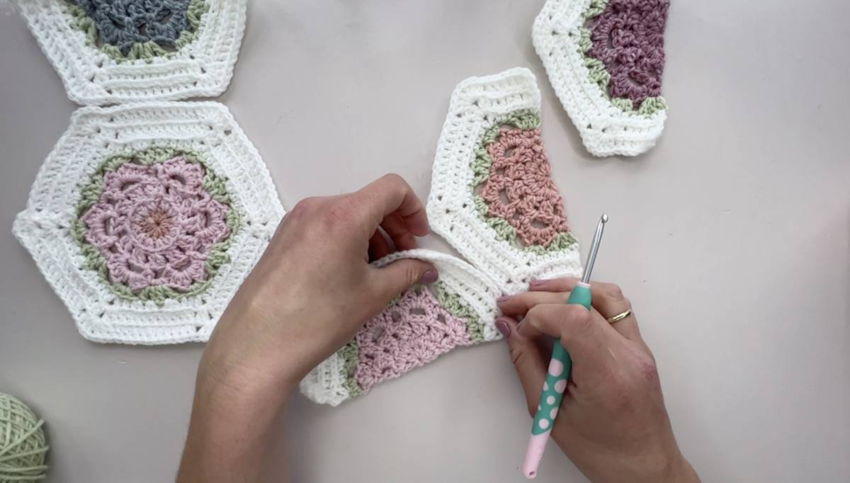 Person showing a a number of crochet hexagons and crochet hook.