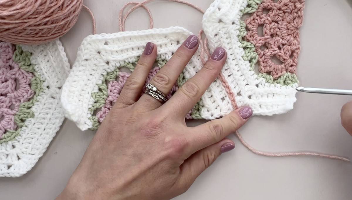 Hands and crochet hook showing flat slip stitch seam.