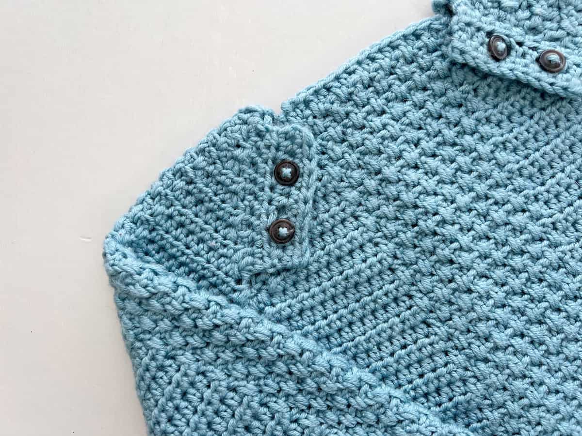 Raglan crochet sweater pattern for babies showing neckline and button fastening details.