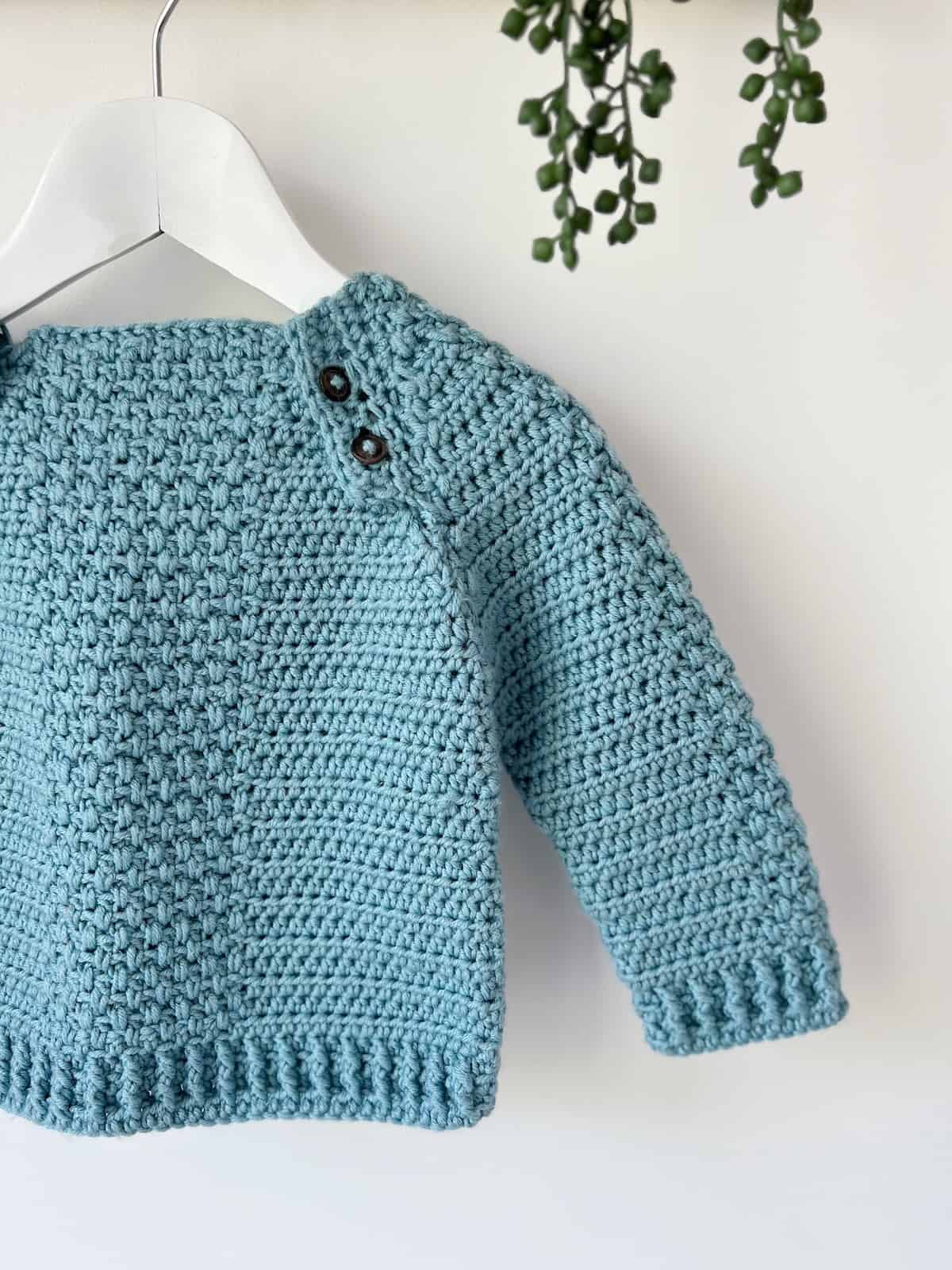 Detailed view of raglan crochet sweater pattern for children with buttons at the front.