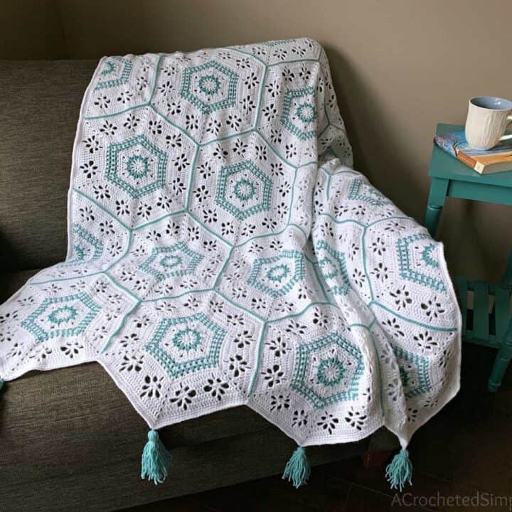 A crocheted hexagon afghan on a chair with tassels.