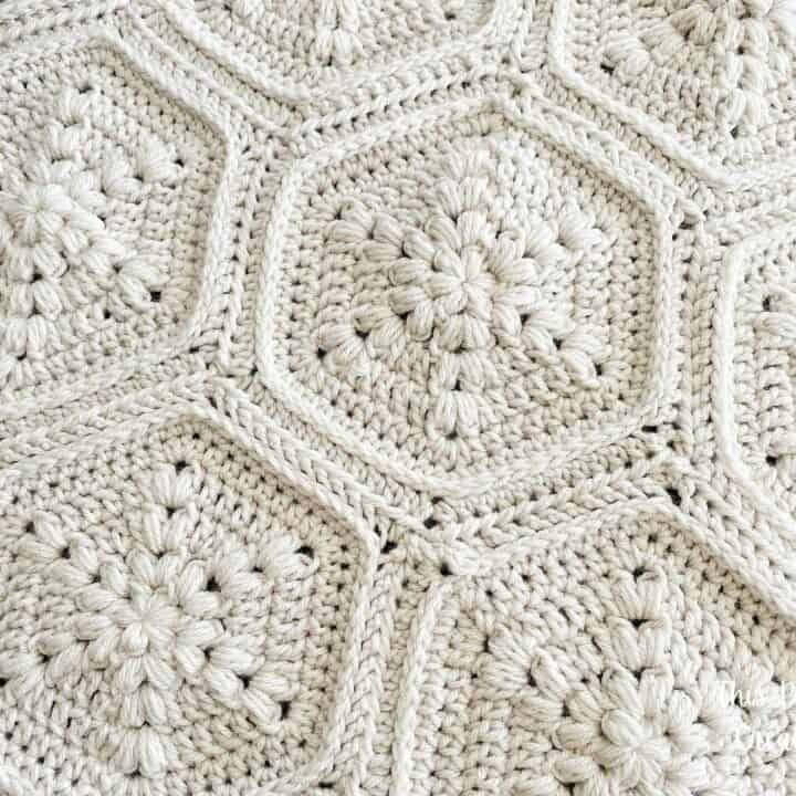 A close up of a white crocheted blanket using hexagons.